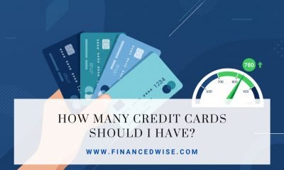 Hand holding a fan of credit cards next to a rising credit score gauge, illustrating how many credit cards you should have